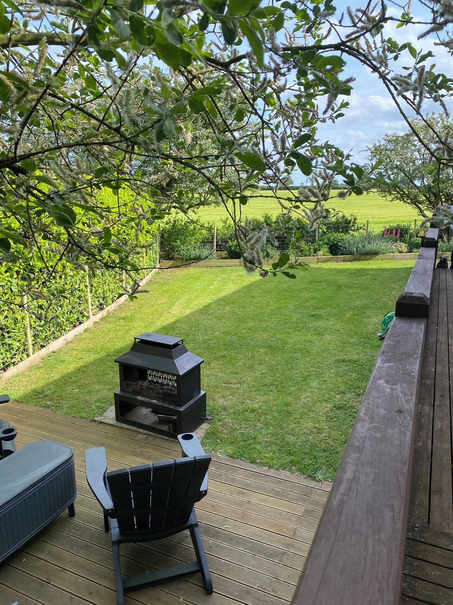 A deck with a grill, a chair, and a view of a grassy yard.