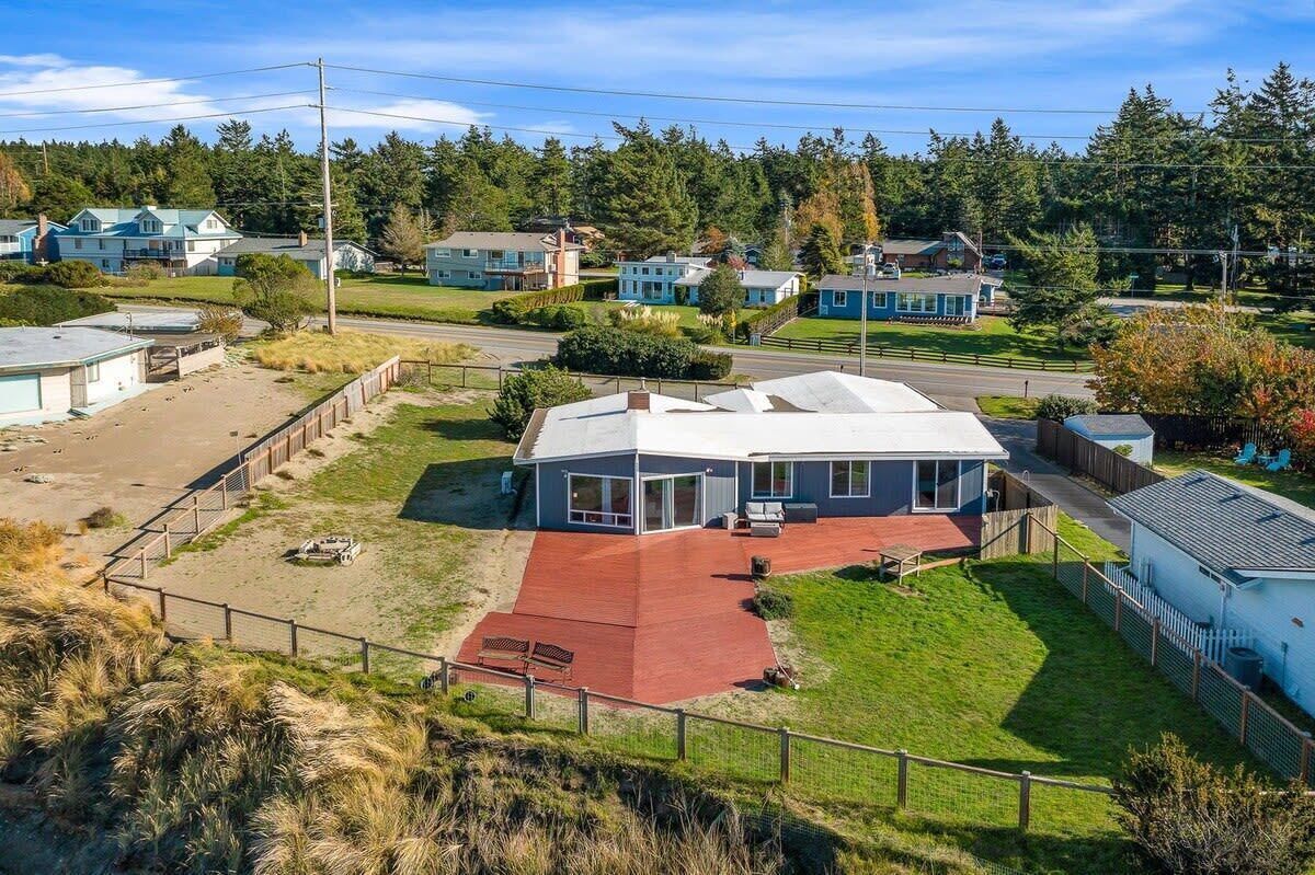 Una casa moderna con techo rojo, patio cercado y vista a casas vecinas.