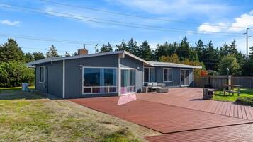 A modern house with a large deck, a covered patio, and a garage.