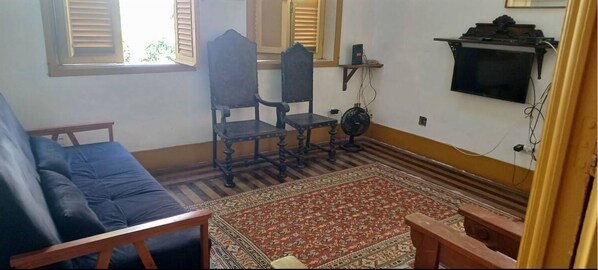Relax in a classic room with a sofa, chair, and television, set against a traditional backdrop.