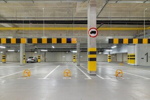 An indoor parking garage with multiple parking spaces, yellow and black striped barriers, and a no truck sign.