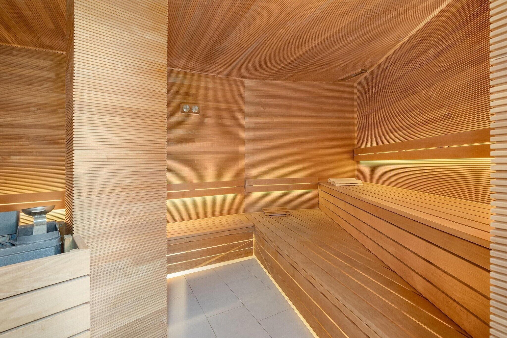 A sauna with wooden slats and benches, a visible heater, and a tiled floor.