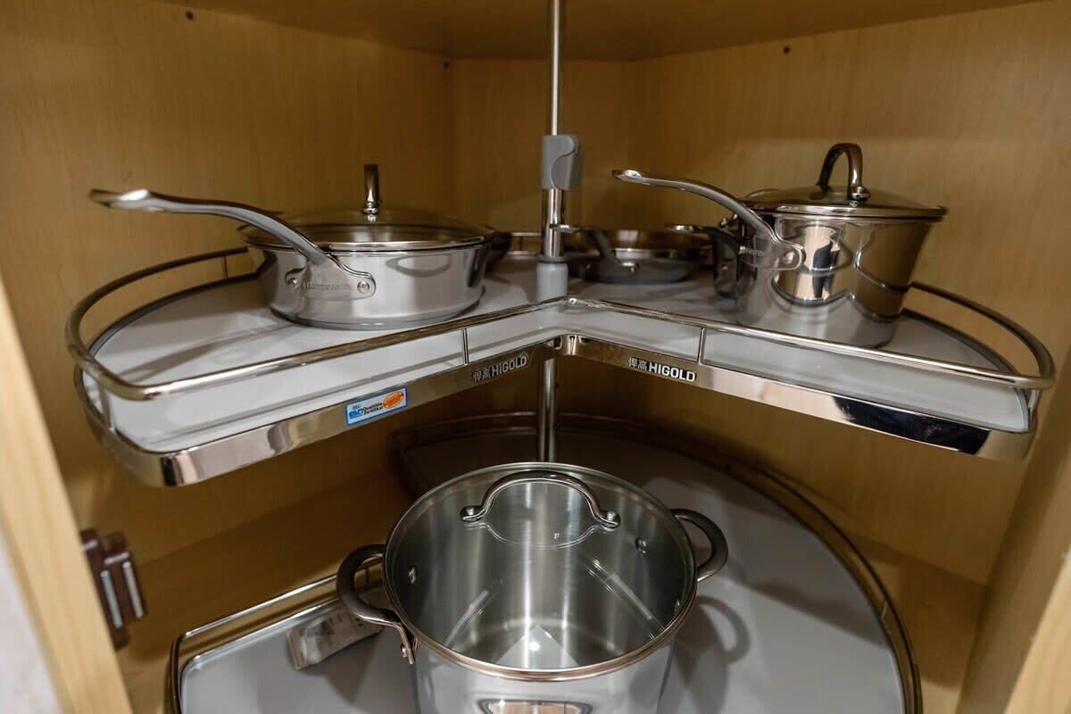 A kitchen with stainless steel cookware on a corner shelf.