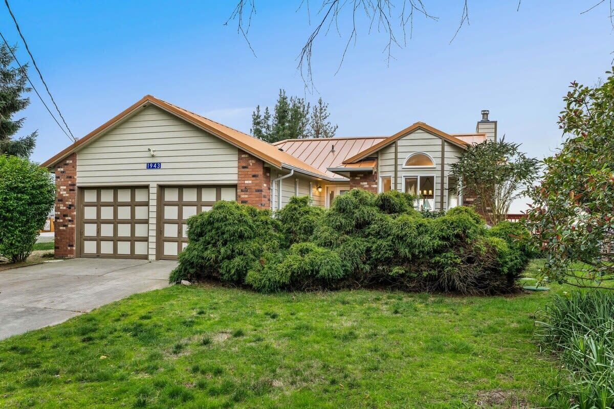 A two-story house with a garage, a brick chimney, and a well-maintained lawn.