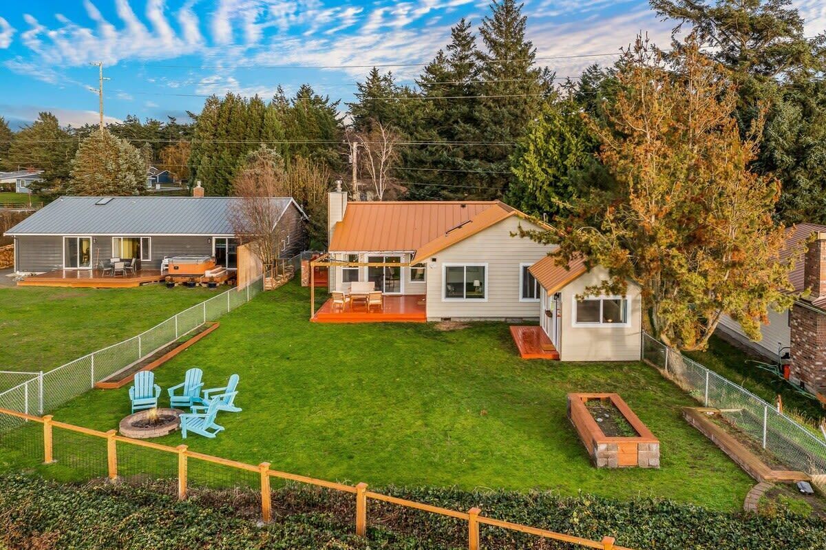 A residential property with a large lawn, a patio area with outdoor furniture, and a small garden.