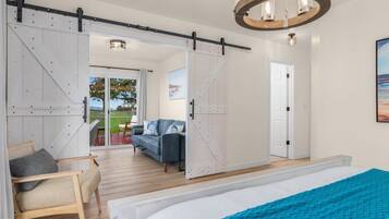 Une chambre avec un grand lit, une porte coulissante de style grange, une vue sur l’extérieur et un lustre.