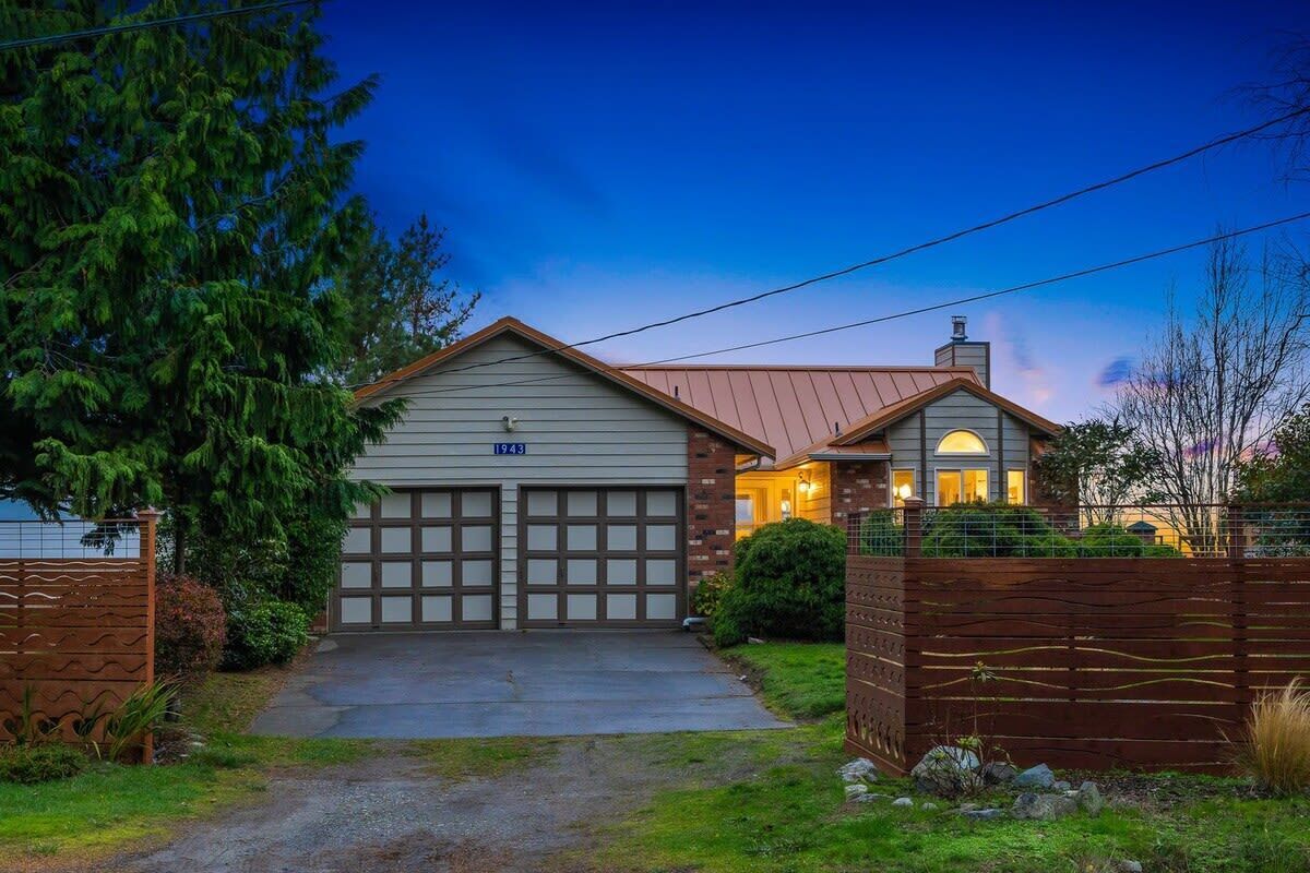 A two-story house with a garage, a covered porch, and a well-maintained lawn.
