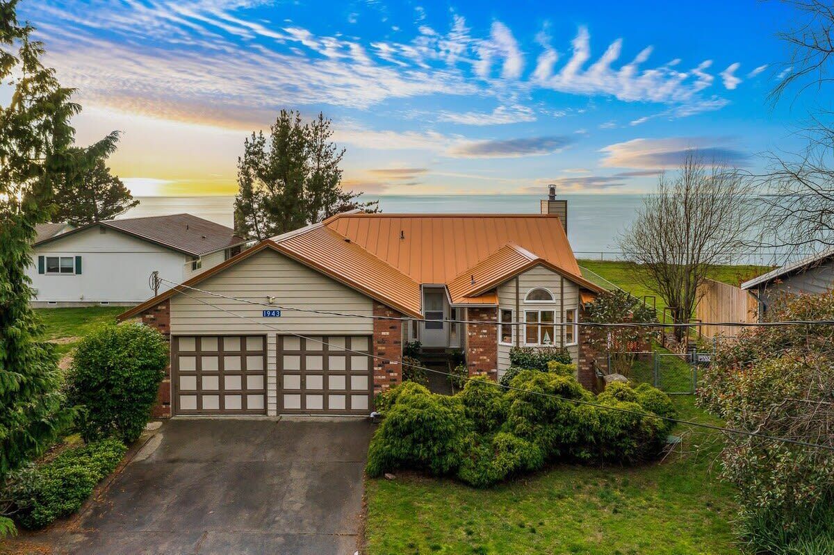 Une maison à deux étages avec un garage, un petit porche et une vue sur l’océan.