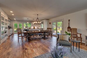 A spacious kitchen with wooden flooring, a dining area with a central island, and a seating area with a sofa and chairs. - @ Marbella Lane - Eccentric 4BR Modern Ranch Home (Reno)
