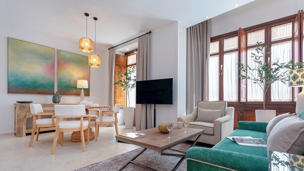 Ein modernes Wohnzimmer mit Couchtisch aus Holz, einem grünen Sofa und einem Fernseher auf einem Lowboard.
