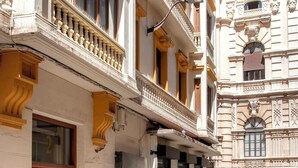Eine Straße mit Gebäuden im Stil der klassischen Architektur, darunter aufwendige Balkone und reich verzierte Fassaden.