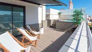 Une terrasse sur le toit, dotée de chaises longues, d’une petite piscine et offrant une vue sur une tour.