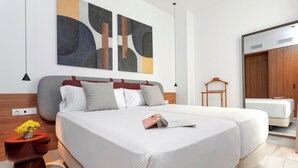 Une chambre d’hôtel moderne avec un grand lit, une armoire en bois et des œuvres d’art abstraites accrochées au mur.