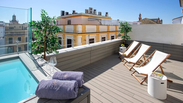 Une terrasse privée avec une piscine, des chaises longues et une petite table avec des serviettes.