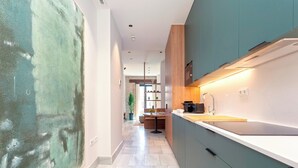 Une cuisine moderne avec des armoires de couleur turquoise, un plan de travail blanc et une grande fenêtre.