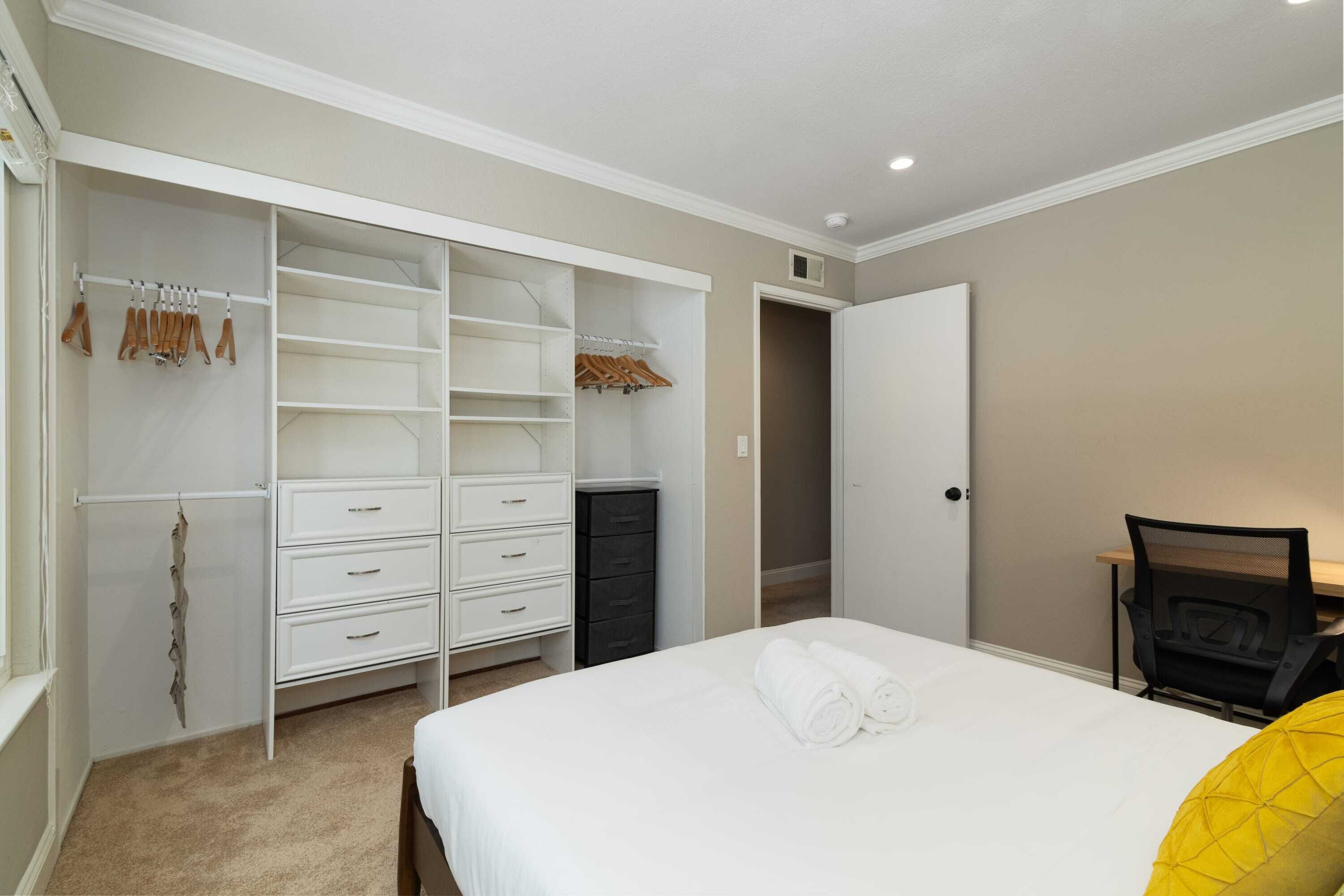 A bedroom with a bed, a wardrobe, a desk, and a chair.