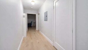 A hallway with white walls, wooden flooring, and a door on the right. - @ Marbella Lane - Spacious 2BR Home Near Westgate  (San Jose)