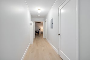 A hallway with white walls and wooden flooring, leading to a dining area with a table and chairs. - @ Marbella Lane - Spacious 2BR Home Near Westgate  (San Jose)