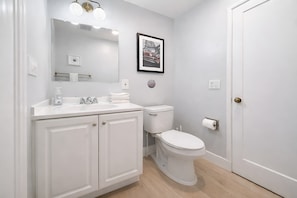 A bathroom with a white sink, mirror, toilet, and a framed picture on the wall. - @ Marbella Lane - Spacious 2BR Home Near Westgate  (San Jose)