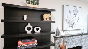 Un salon moderne avec une bibliothèque en bois foncé, une cheminée et un tableau représentant des motifs floraux.