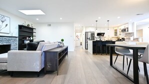 Une cuisine moderne avec des meubles blancs, un îlot central et un coin repas comprenant une table et des chaises.