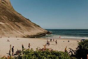 Een strand met mensen, een klif en de oceaan.