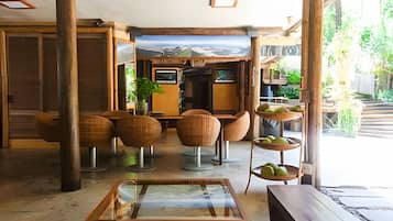 Um interior amplo com mobiliário de madeira, uma mesa de vidro e vista para uma paisagem nevada através de grandes janelas.