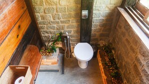 Un baño pequeño con un banco de madera, un inodoro blanco y un lavamanos.