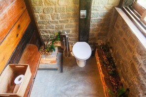 Un baño pequeño con un banco de madera, un inodoro blanco y un lavamanos.