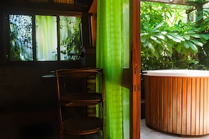A room with a wooden chair, a wooden hot tub, and a window with a view of greenery. - Ypê Greenhouse (Niteroi)