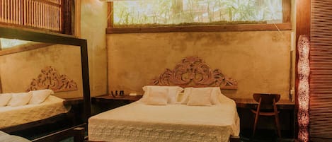Una habitación con una cama de madera, una silla de madera, una mesita y una ventana con vistas a la vegetación.