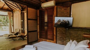Una habitación de hotel con cama, televisión, armario de madera y zona de estar con sillas.