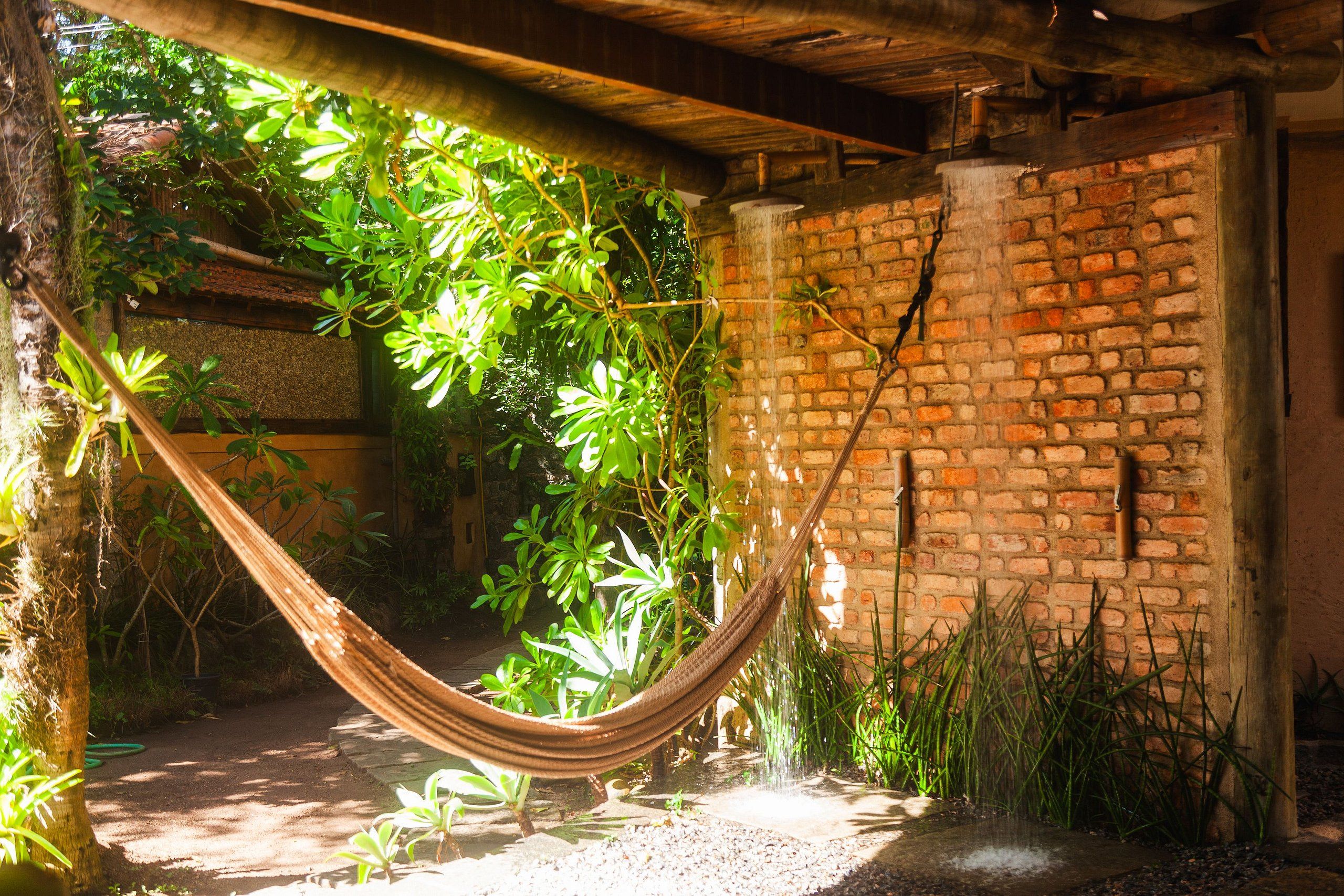 Una hamaca en un jardín exuberante, con un muro de ladrillo y follaje.