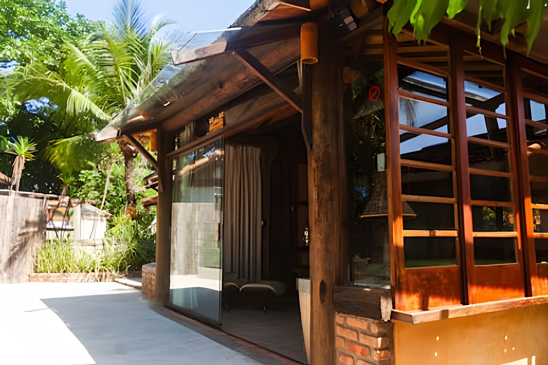 A wooden building with a glass door and windows, surrounded by greenery.