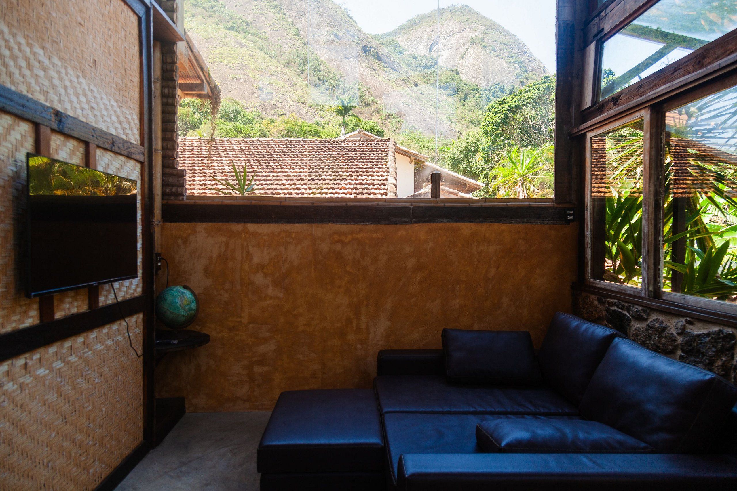 Quarto com vista para uma montanha, televisão e sofá.