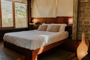 A wooden bed with white bedding, two bedside lamps, and a view of greenery outside. - Ypê Greenhouse (Niteroi)