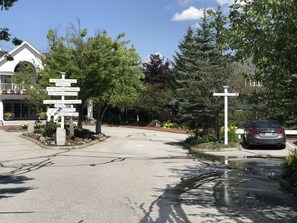 A street view with a directional signpost listing various local attractions and a parked car.