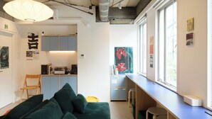 Un intérieur moderne avec un canapé vert, un fauteuil jaune et un coin bar équipé de tabourets.