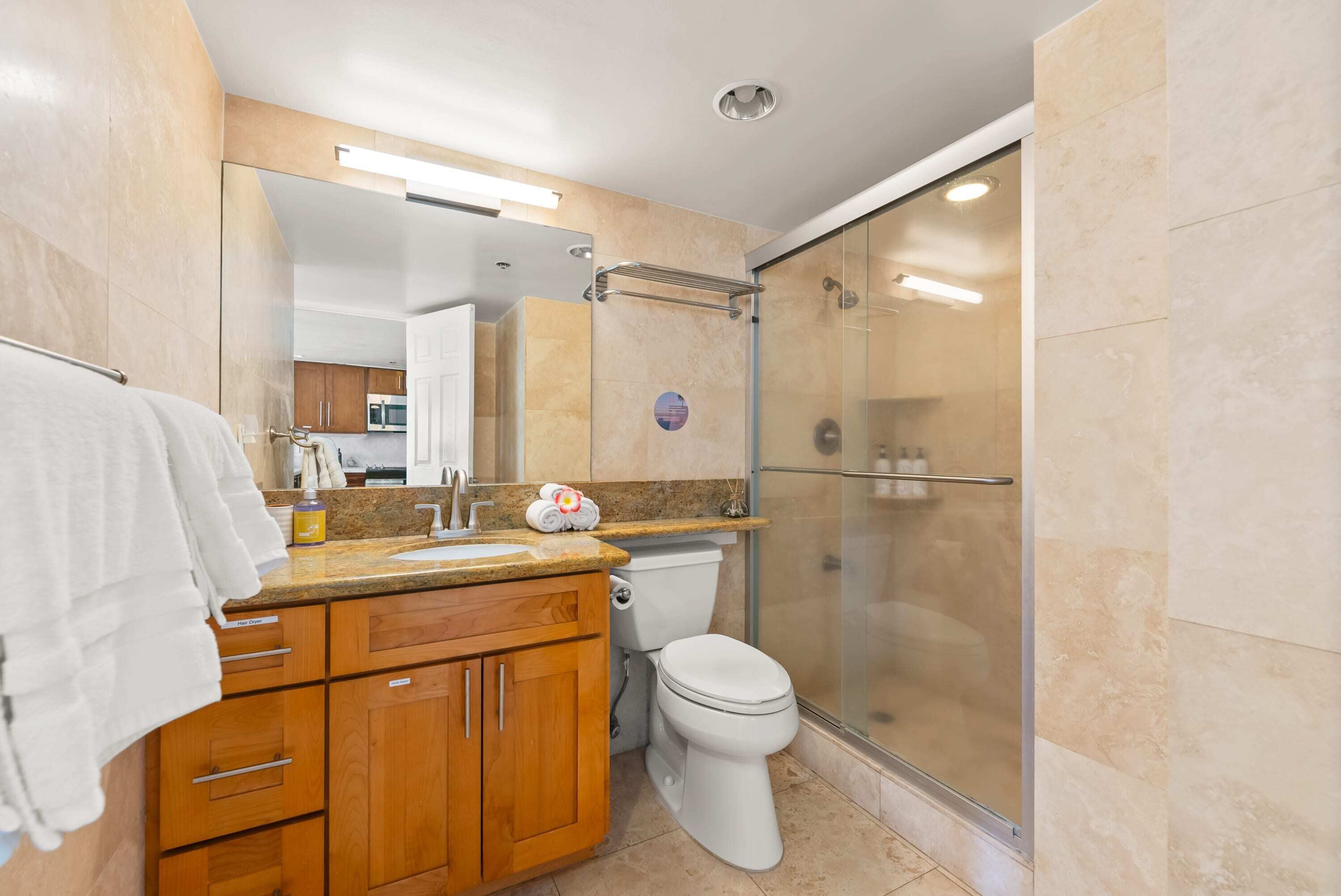 Un bagno moderno con un mobile bagno in legno, un water e una cabina doccia in vetro.