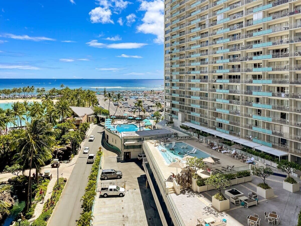 Um hotel moderno com várias varandas, piscina e vista para a praia.