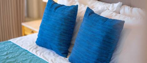 A bed with a teal quilt and two blue pillows.