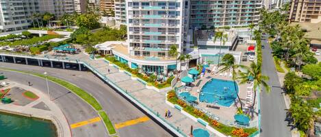 A high-rise hotel with a rooftop pool, multiple balconies, and a landscaped terrace.
