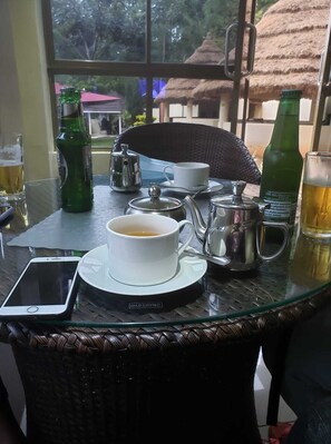 A table with a cup of tea, a teapot, a bottle of beer, a smartphone, and a glass of beer. - The Village Park Resort & Spa (Keumbu)