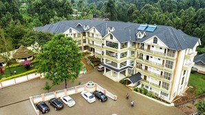 Un hôtel à plusieurs étages doté d’une cour intérieure, d’un parking et entouré d’un paysage verdoyant luxuriant.