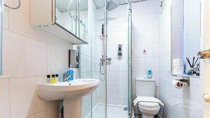 Ein modernes Badezimmer mit einer Duschkabine, einem Standwaschbecken und einer Toilette.