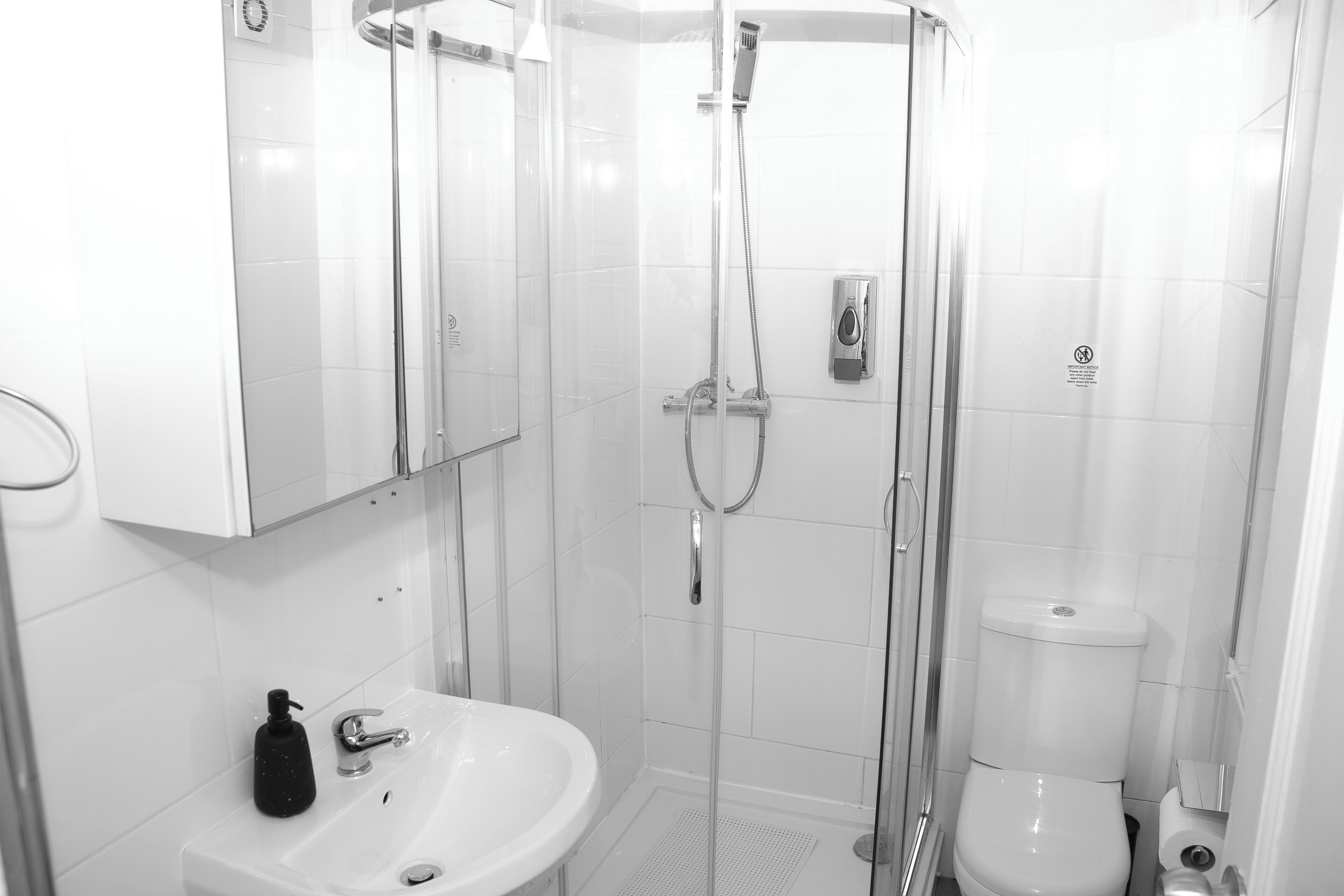 A modern bathroom with a glass-enclosed shower, a white sink, and a toilet.