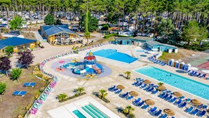 An aerial view of a resort with a large swimming pool, a water park, and a beach area with sun loungers.