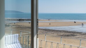 A beach view from a balcony with a railing, a sandy beach, and the ocean. - 9 Strandways - Sea Views, Parking, Beach Access (Saundersfoot)