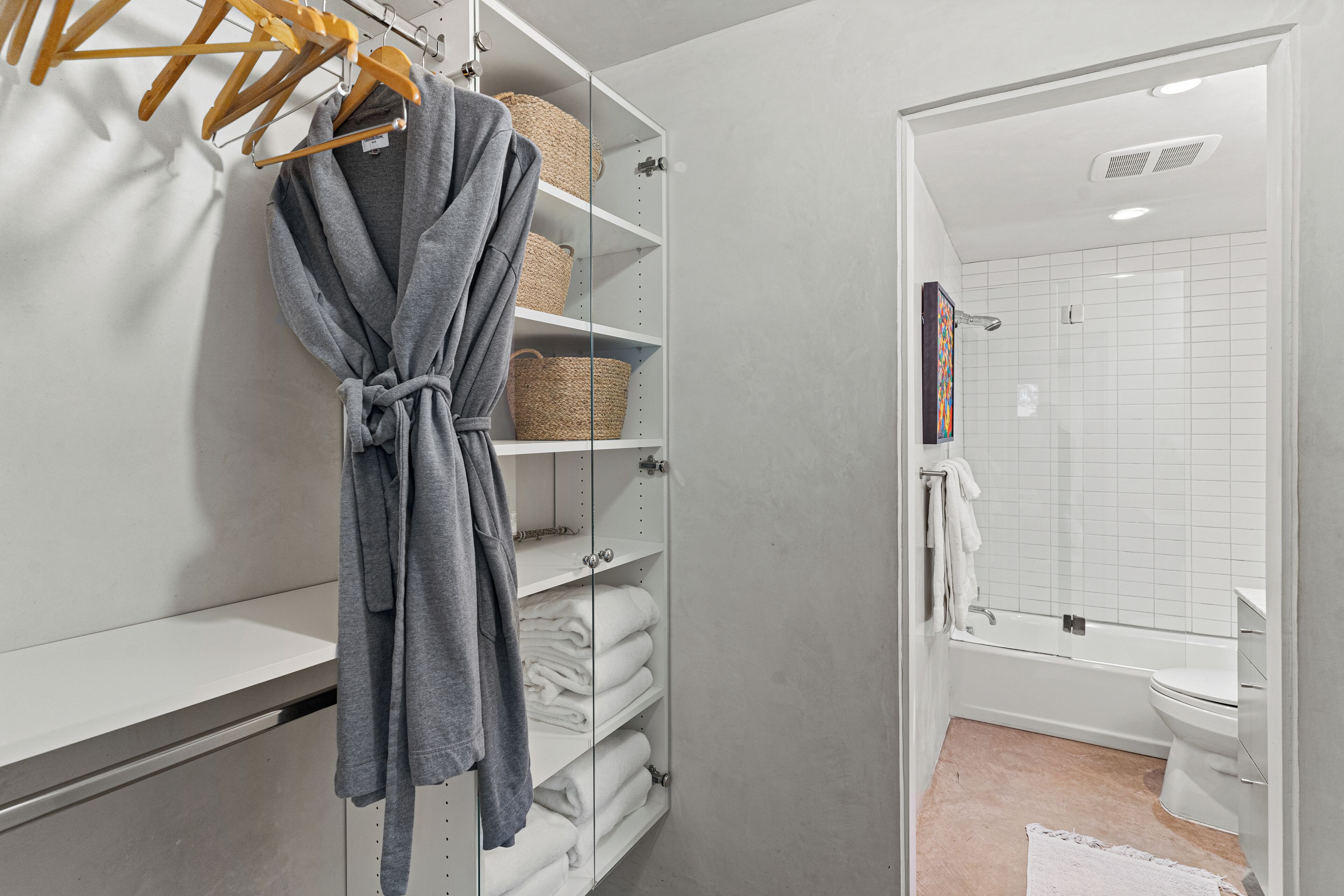A bathroom with a shower, toilet, and a towel rack with a robe.