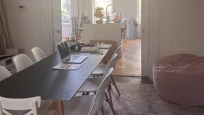 Ein Essbereich mit einem langen Tisch, weißen Stühlen und einem rosa Sitzsack.